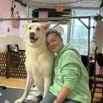 Madison sitting with a large white dog on the grooming table